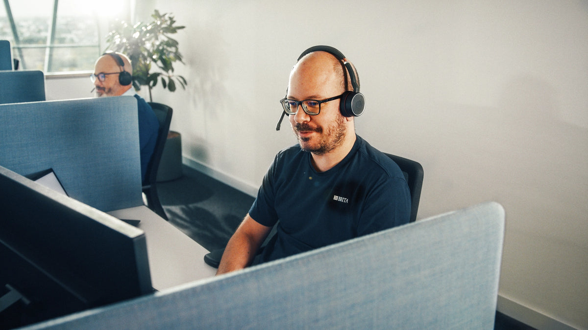 Person wearing a headset and working in an office setting.